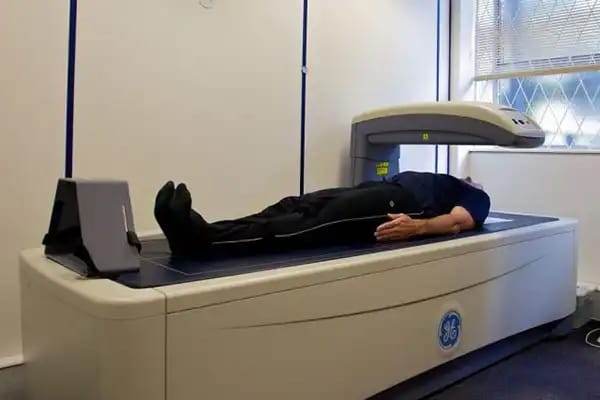 A man undergoing a Dual-Energy X-ray Absorptiometry (DEXA) scan, a gold standard method for body composition measurement.
