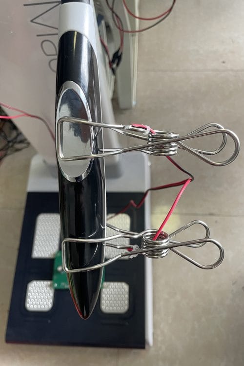 The iBodyinfo RES-MODER BIA calibration fixture being used to validate the performance of a body composition analyzer's handheld electrodes.