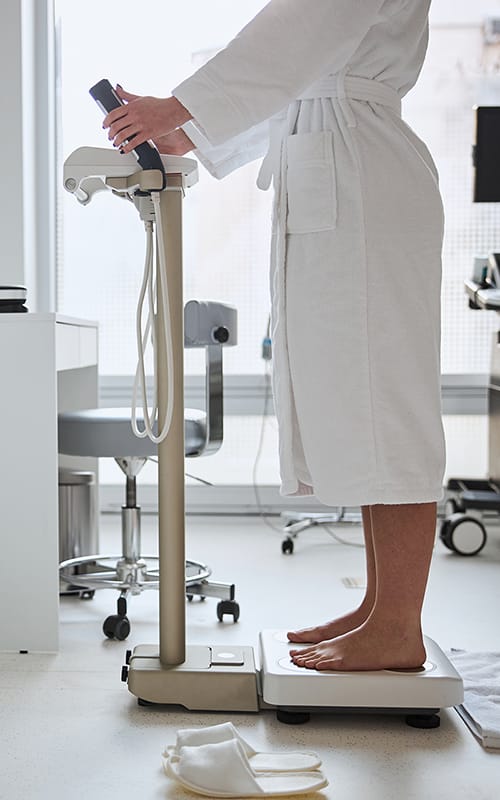 A user maintains the correct standing posture on a professional BIA scale during a body composition analysis.