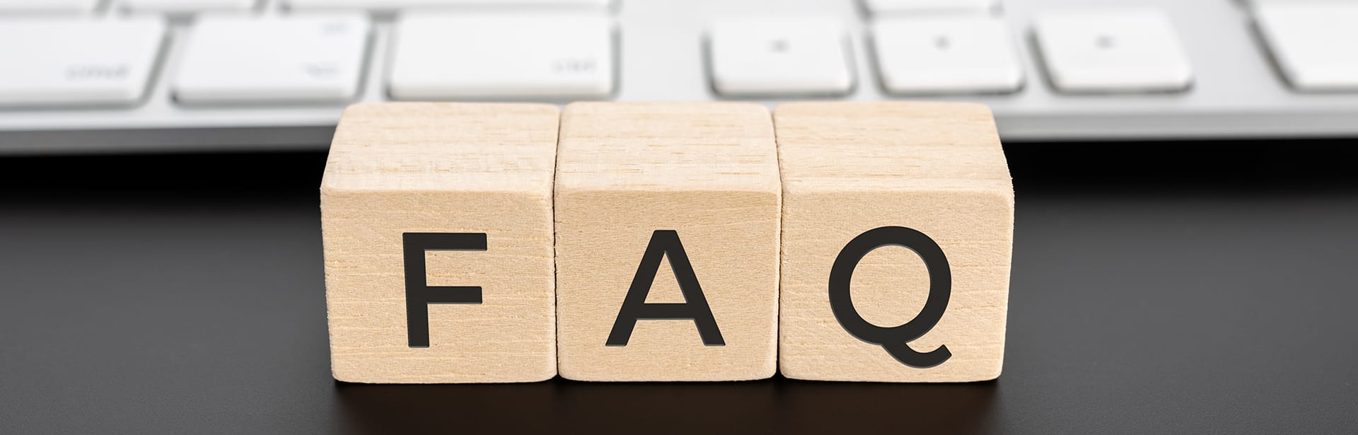 Wooden blocks spelling out 'FAQ' in front of a keyboard, representing the frequently asked questions section for iBodyinfo's BIA measurement modules and technical solutions.