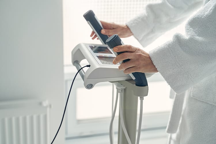 A client undergoes a precise segmental measurement using an 8-electrode body composition analyzer in a professional clinical setting.